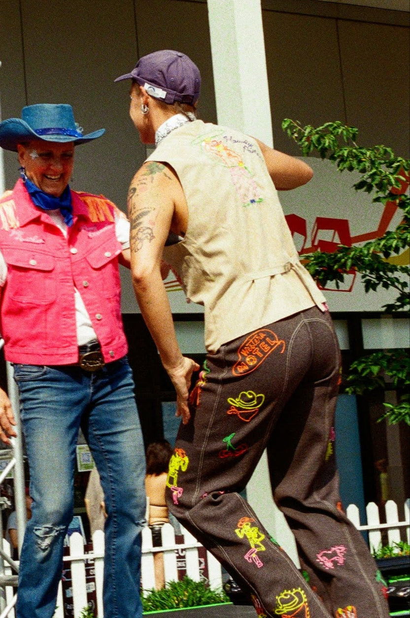 Two people on a stage with a 'Recycled Rodeo' sign in the background